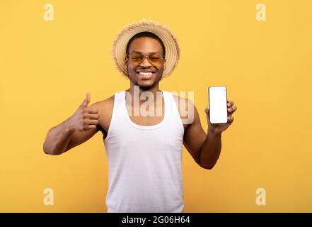 Check out this new mobile application. Happy guy showing cellphone with mockup for website or app, gesturing thumb up Stock Photo