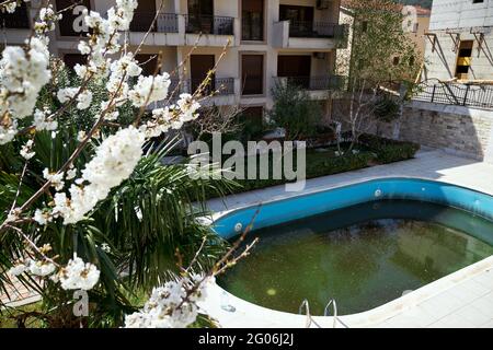 Dirty backyard swimming pool, muddy dark water before cleaning. Stock Photo