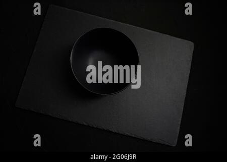Empty black ceramic bowl over a dark slate background Stock Photo