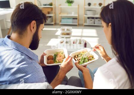 Young couple man and woman office workers sitting and enjoying healthy boxed food order Stock Photo