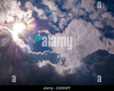 Sun with rays in the blue sky and thick clouds Stock Photo