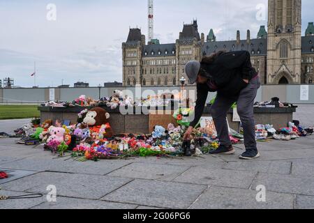 Ottawa, Canada. June 1st, 2021. A memorial to the 215 children found buried at a former Kamloops, British Columbia residential school laid at the Centennial Flame in front of the Canadian Parliament. People have been bringing kids shoes, stuffed animals and flowers to pay respect to the children whose bodies were uncovered in the grounds of the former Kamloops Indian Residential School as Canadians continue to wrestle with the history of Aboriginal Residential Schools throughout the country, as well as the historical treatment of First Nations communities. Credit: meanderingemu/Alamy Live News Stock Photo