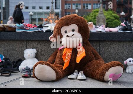 Ottawa, Canada. June 1st, 2021. A memorial to the 215 children found buried at a former Kamloops, British Columbia residential school laid at the Centennial Flame in front of the Canadian Parliament. Children shoes and stuffed animal with orange scarf to pay respect to the children whose bodies were uncovered in the grounds of the former Kamloops Indian Residential School as Canadians continue to wrestle with the history of Aboriginal Residential Schools throughout the country, as well as the historical treatment of First Nations communities. Stock Photo