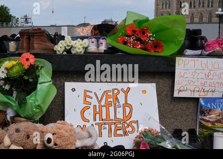 Ottawa, Canada. June 1st, 2021. A memorial to the 215 children found buried at a former Kamloops, British Columbia residential school laid at the Centennial Flame in front of the Canadian Parliament. People have been bringing kids shoes, stuffed animals and flowers to pay respect to the children whose bodies were uncovered in the grounds of the former Kamloops Indian Residential School as Canadians continue to wrestle with the history of Aboriginal Residential Schools throughout the country, as well as the historical treatment of First Nations communities. Credit: meanderingemu/Alamy Live News Stock Photo