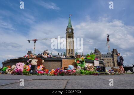 Ottawa, Canada. June 1st, 2021. A memorial to the 215 children found buried at a former Kamloops, British Columbia residential school laid at the Centennial Flame in front of the Canadian Parliament. People have been bringing kids shoes, stuffed animals and flowers to pay respect to the children whose bodies were uncovered in the grounds of the former Kamloops Indian Residential School as Canadians continue to wrestle with the history of Aboriginal Residential Schools throughout the country, as well as the historical treatment of First Nations communities. Credit: meanderingemu/Alamy Live News Stock Photo