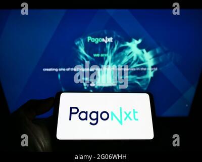 Person holding cellphone with logo of Spanish financial services company PagoNxt on screen in front of business webpage. Focus on phone display. Stock Photo