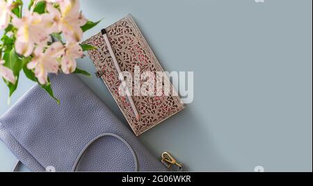Flat lay of blue working table background with planner, pencil , elegant female cross body bag and plants . Top view, mock up greeting card, craft Not Stock Photo
