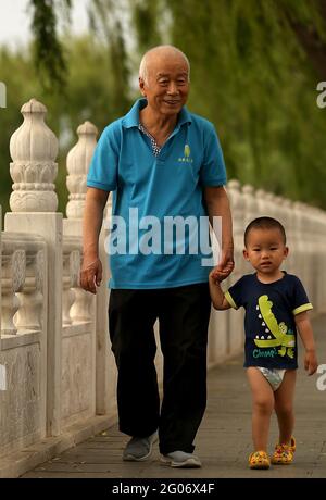 Beijing, China. 01st June, 2021. A grandfather walks with his grandson along a lake in Beijing on Tuesday, June 1, 2021. China says it will allow couples to have three children, up from two, as the Communist Party attempts to reverse declining birthrates and aver a population crisis, but experts say it is woefully inadequate. Photo by Stephen Shaver/UPI Credit: UPI/Alamy Live News Stock Photo