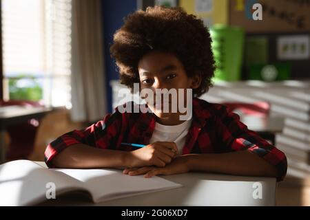 Portrait of african american boy siting on his desk in class at elementary school Stock Photo