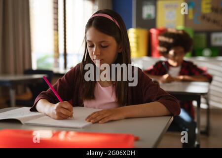 Caucasian girl studying while siting on his desk in class at elementary school Stock Photo