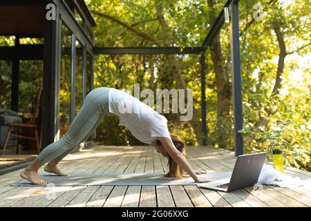 Asian woman practicing yoga using laptop on terrace in garden Stock Photo