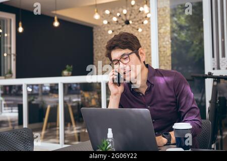 Asian businessman using smartphone and laptop in hotel lobby Stock Photo