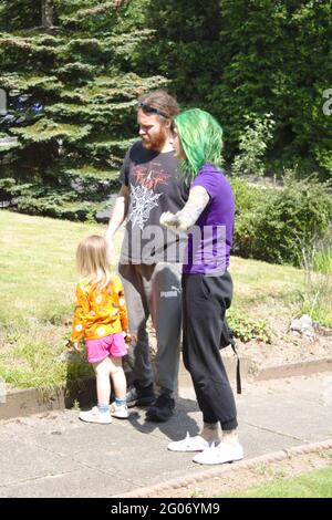 Young happy family walking outdoors. One Parent has green hair Stock Photo