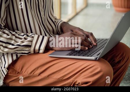 Close-up of African man typing on laptop while sitting at office Stock Photo