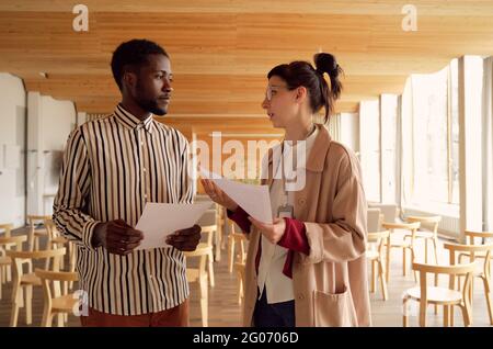 Two young business people discussing documents together at office Stock Photo