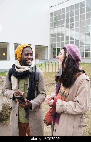 Two young friends talking and smiling while walking in the city Stock Photo