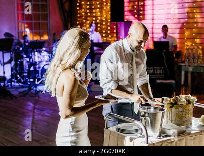 Bride and groom cutting wedding cake at wedding reception. Stock Photo
