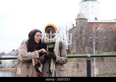 Young couple of tourists using mobile phone while standing in the city Stock Photo