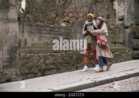 Two tourists using mobile phone while travelling in old city Stock Photo