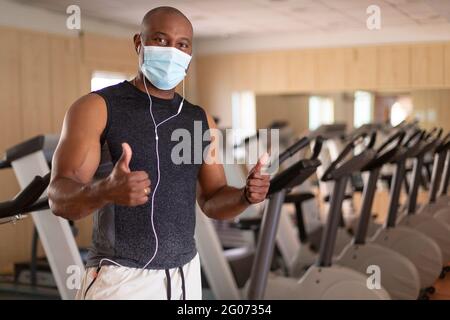 Portrait of black male sportsman with face mask. He is inside the gym in a positive attitude. Concept of sport during the Covid-19 pandemic. Stock Photo