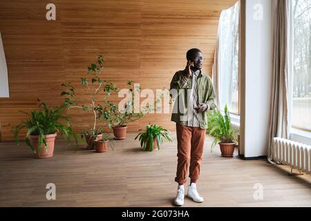 African young man talking on mobile phone while standing at modern office hall Stock Photo