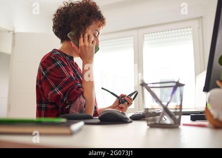 Woman teleworking at an adjustable standing desk and talking on the phone Stock Photo