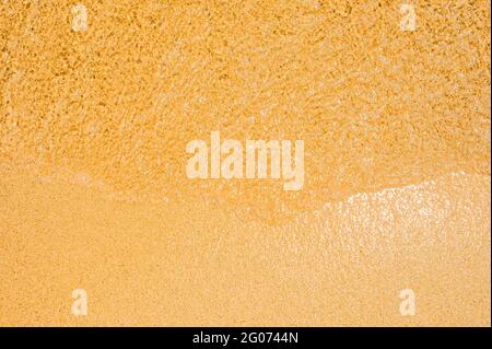 wet sand texture. Small wave of water on clear sandy beach. Sand beach and wave. Golden sand texture, top view Stock Photo