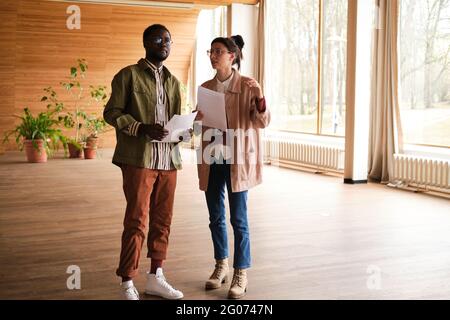 Two designers discussing project together while standing in empty room Stock Photo