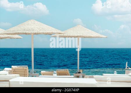 beach of the hotel resort, beach umbrellas and sun loungers against the backdrop of the beautiful sea. Empty beach sea summer background. vacation con Stock Photo