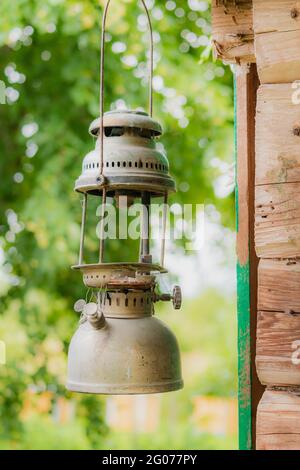 Old, broken and rusty oil lamps hanging near the old wooden wall. Lithuanian village at summer season Stock Photo