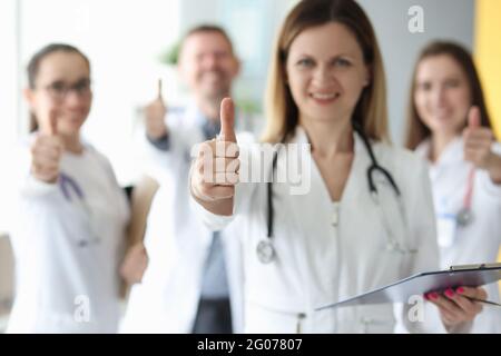 Successful medical team in white coats hold their thumbs up Stock Photo