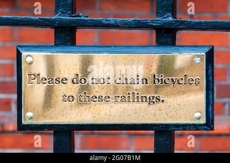 A brass plaque reading Please do not chain bicycles to these railings. Stock Photo