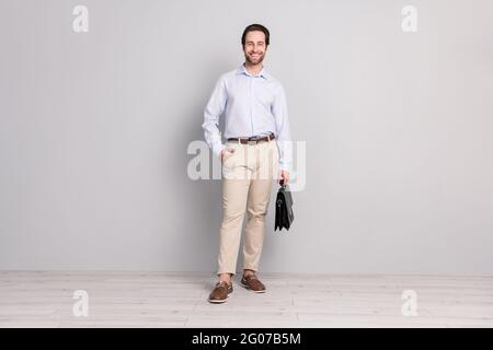 Full length body size photo confident business man wearing white shirt smiling keeping paper bag isolated grey color background Stock Photo