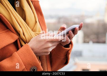 Close-up of woman in warm clothing holding mobile phone in her hands Stock Photo