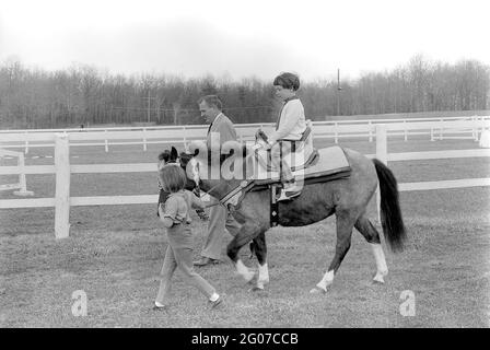 31 March 1963 Sally Fay riding horse 'Macaroni' lead by Paul 'Red' Fay and Caroline Kennedy. 'Macaroni' wears a Moroccan saddle given to the Kennedy's by King Hassan II of Morocco. Camp David, Maryland. Stock Photo