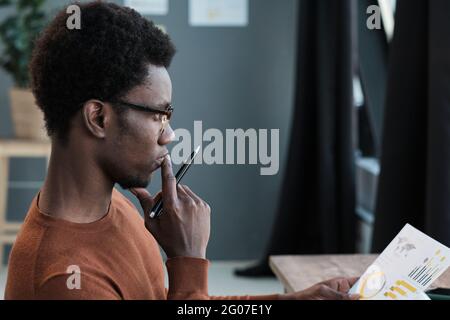 African student in eyeglasses sitting with pensive look and preparing for exams Stock Photo