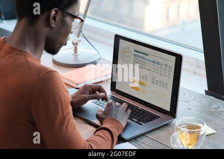 Rear view of African businessman typing financial documents on laptop at office Stock Photo