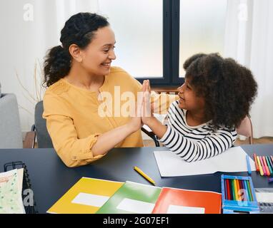 Child psychologist gives five an African American little girl during a psychotherapy session. Care of children's mental health Stock Photo