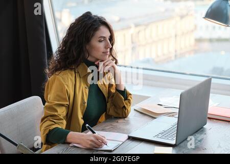 Young businesswoman sitting at the table working with documents and using laptop she working at office Stock Photo
