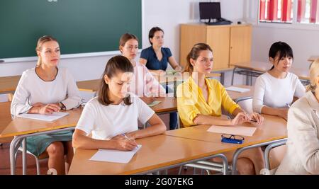 Students writing in notepads during lesson Stock Photo