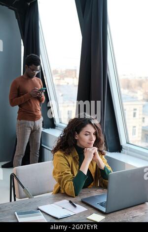 Young businesswoman working on computer with man standing in the background they working at office Stock Photo