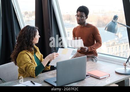 Two business colleagues working with documents in team and planning work while sitting at office Stock Photo