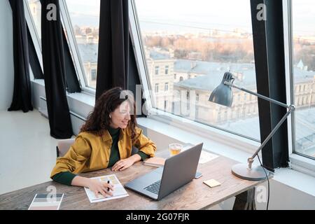 Young businesswoman sitting at the table working with documents and laptop while working at office Stock Photo