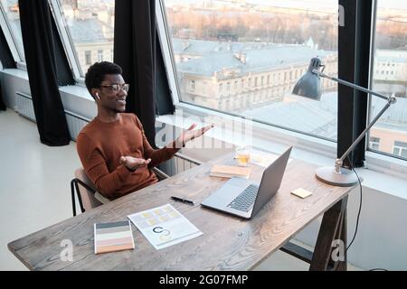 African businessman sitting at his workplace and talking online on computer during work at office Stock Photo