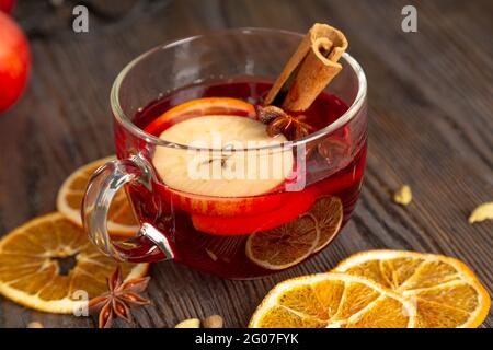 Mulled wine with spices and fruit on a brown wooden table. Traditional Christmas hot drink with red wine, apples, oranges and cinnamon Stock Photo