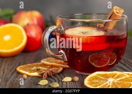 Mulled wine with spices and fruit on a brown wooden table. Traditional Christmas hot drink with red wine, apples, oranges and cinnamon Stock Photo