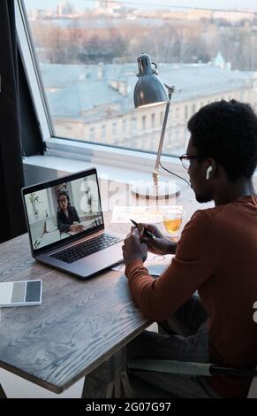 Rear view of businessman talking to his colleague on laptop during online meeting Stock Photo