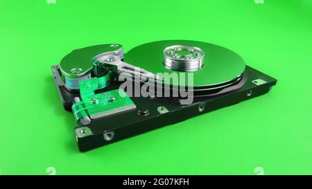 Disassembled hard drive close up with plates visible on green background with green reflection Stock Photo