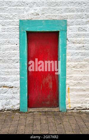 Blocked-up red painted door in green painted stone surround Stock Photo