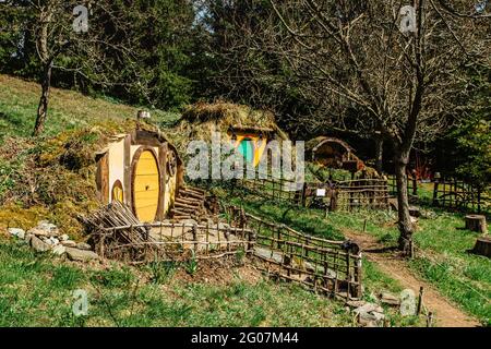 Hobbit house in Czech Hobbiton with three Hobbit holes and cute yellow green doors.Fairy tale home in garden.Magic small village from fantasy movie lo
